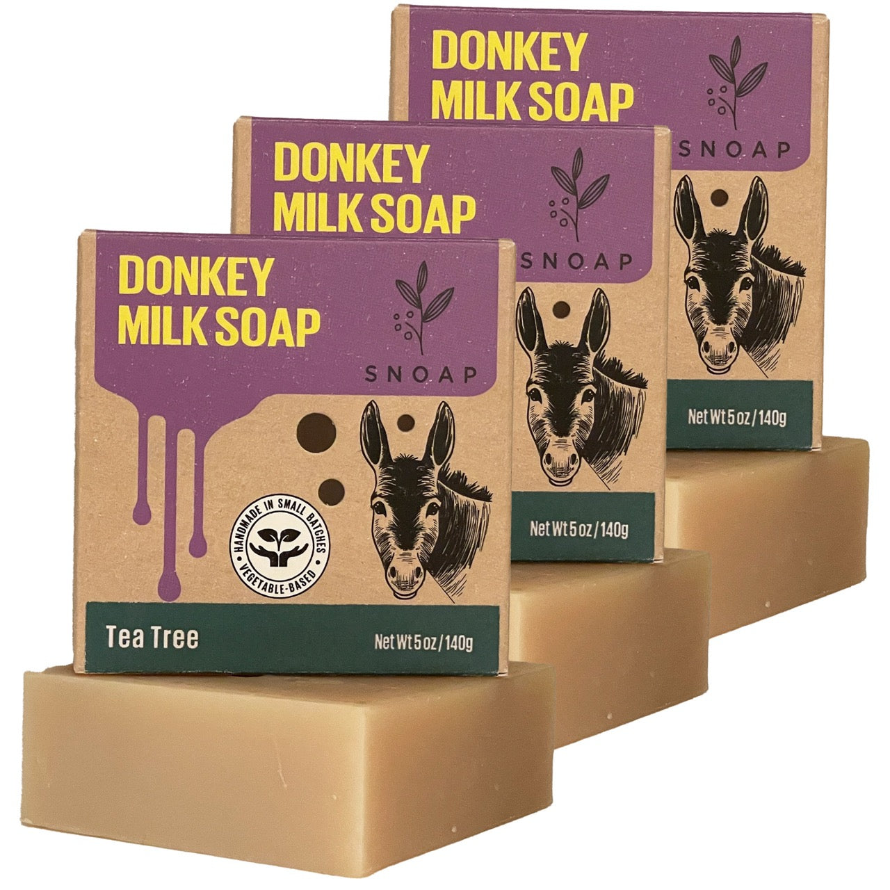 Three bars of tea tree donkey milk soap with a light tan color are stacked in a staggered formation, each below its cardboard box packaging. The boxes are decorated with a sketch of a donkey and the text 'Donkey Milk Soap' and 'SNOAP'.